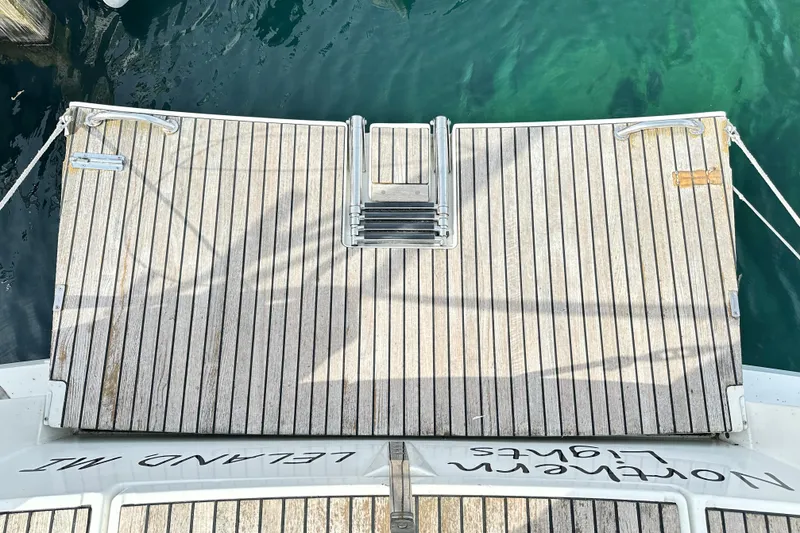 Slide: The Image of Jeanneau Sun Odyssey 469 (2015) yacht stern with wooden deck and ladder, docked in clear water. - 36