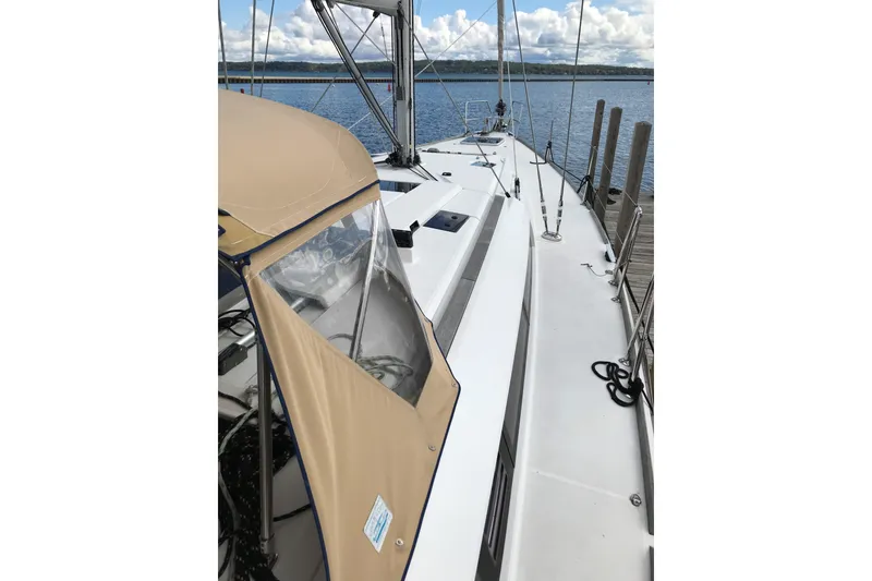 Slide: The Image of 2015 Jeanneau Sun Odyssey 469 sailboat docked, featuring a beige canopy and sleek deck design. - 4