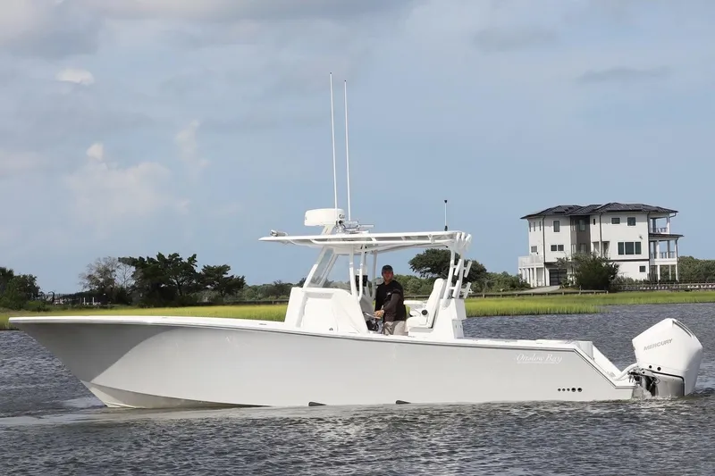 Slide: The Image of 2022 Onslow Bay 33 boat cruising on a calm waterway near a modern house. - 5