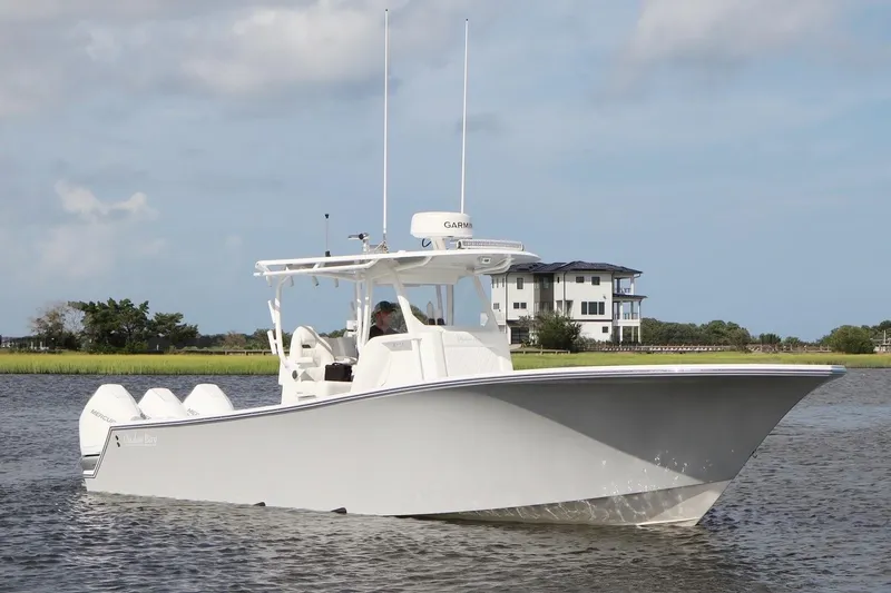 Slide: The Image of 2022 Onslow Bay 33 boat cruising on a calm waterway near a modern house. - 6