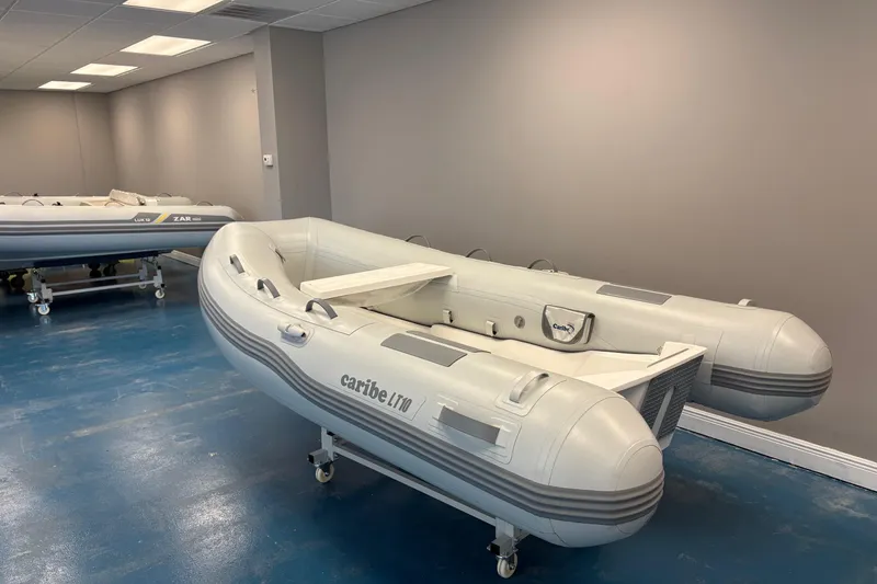 Slide: The Image of Inflatable Caribe L-10 boat, 2025 model, displayed indoors with promotional signage. - 3