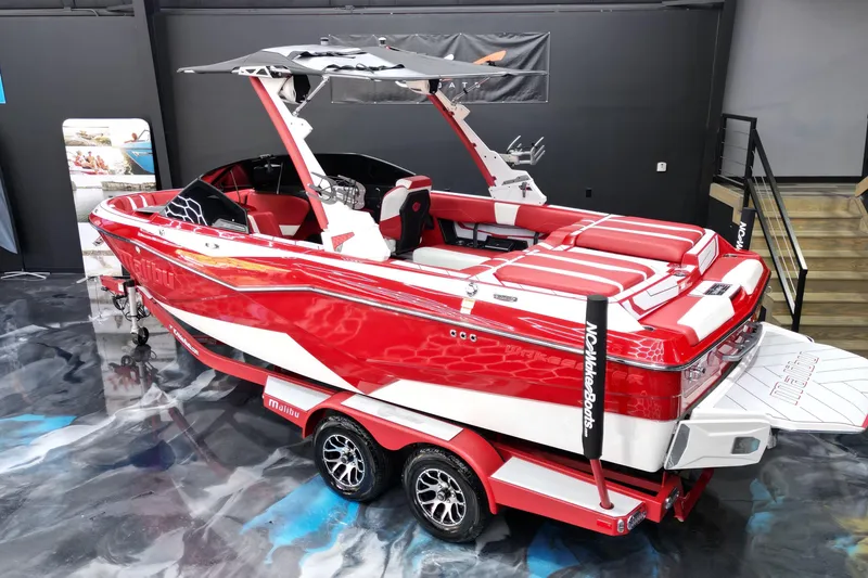 Slide: The Image of 2023 Malibu Wakesetter 22 LSV boat, red and white, displayed indoors on a trailer. - 12