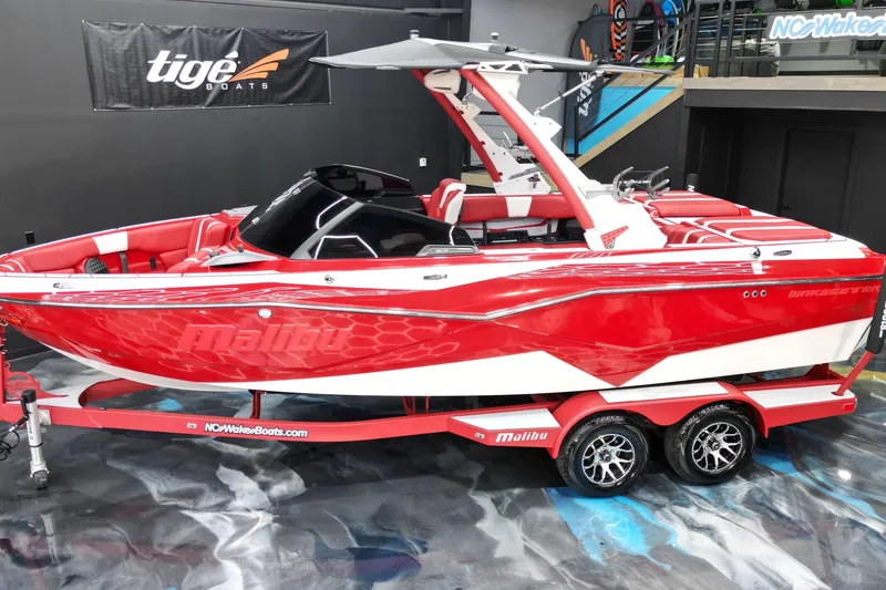 Slide: The Image of 2023 Malibu Wakesetter 22 LSV boat in vibrant red and white, displayed indoors. - 14