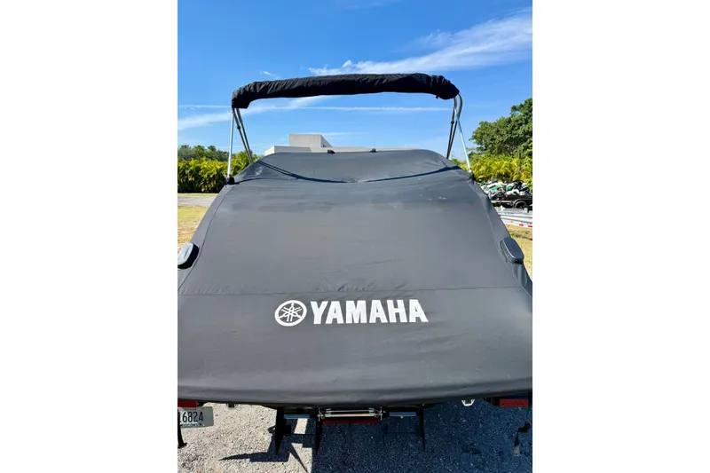 Slide: The Image of 2024 Yamaha SX250 boat with cover, parked outdoors under clear blue sky. - 32