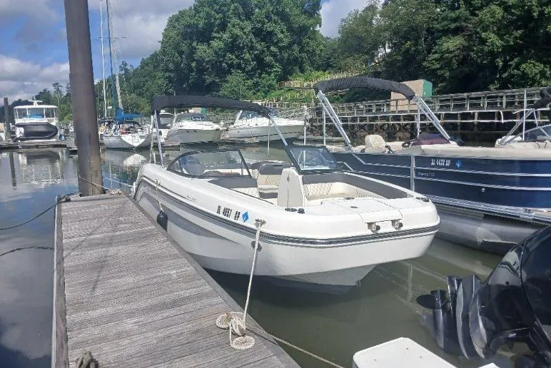 The Image of 2023 Bayliner DX 2200 boat docked at a marina with other vessels. - 1