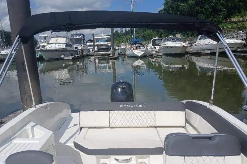 Slide: The Image of 2023 Bayliner DX 2200 boat docked in a marina with other boats. - 10