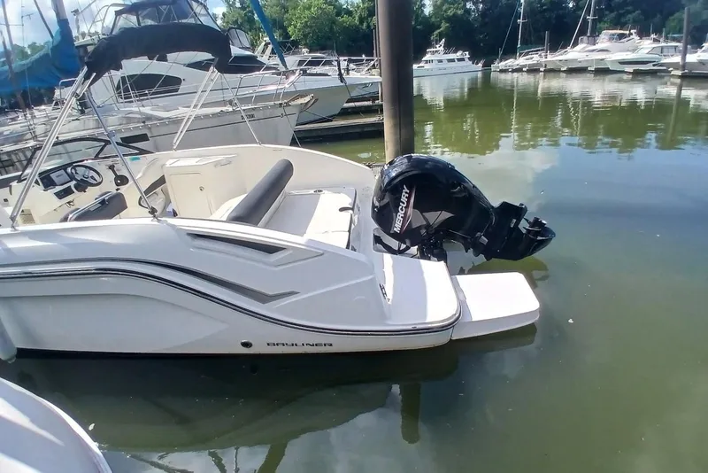 Slide: The Image of 2023 Bayliner DX 2200 boat docked with Mercury outboard motor in a marina. - 11