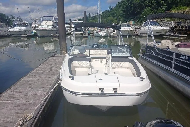 Slide: The Image of 2023 Bayliner DX 2200 boat docked at a marina with other vessels. - 3