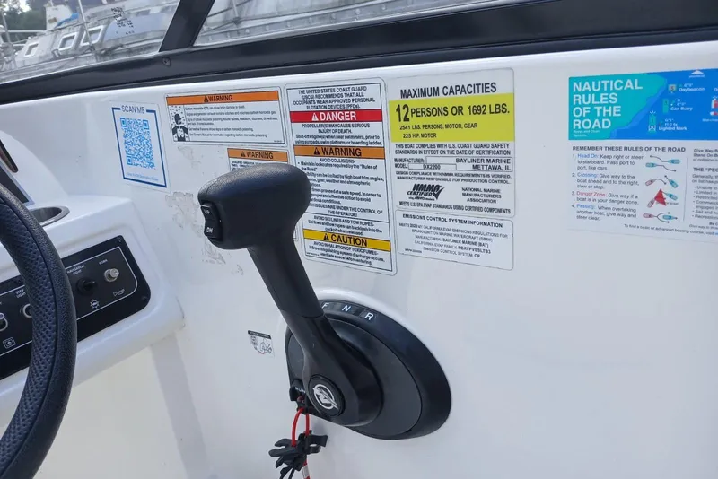 Slide: The Image of 2023 Bayliner DX 2200 boat controls with safety and capacity labels. - 6