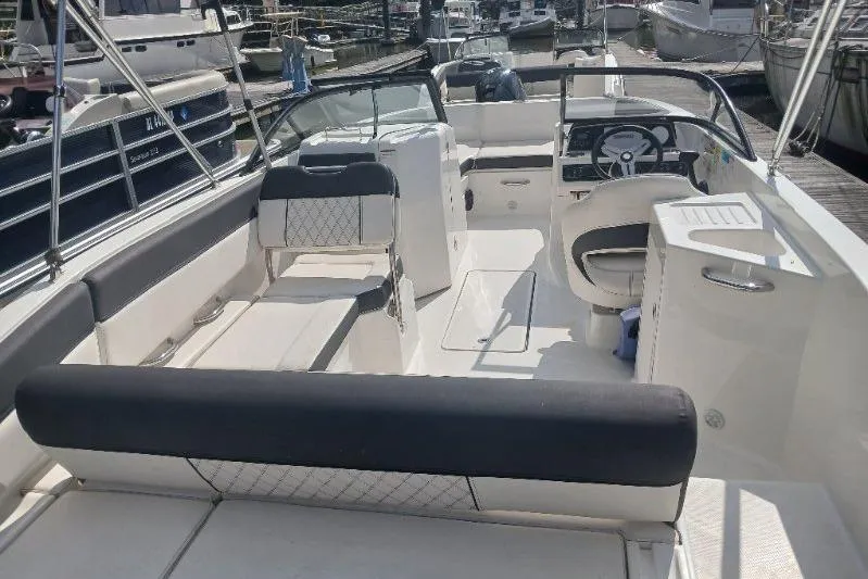 Slide: The Image of 2023 Bayliner DX 2200 boat interior with seating and steering wheel at a marina. - 7