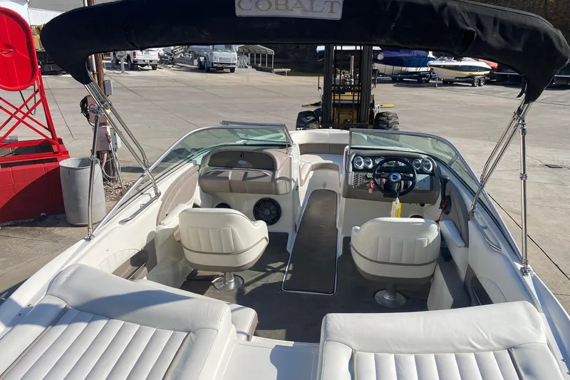Slide: The Image of 2004 Cobalt 220 boat interior with white seating and steering wheel, docked outdoors. - 7
