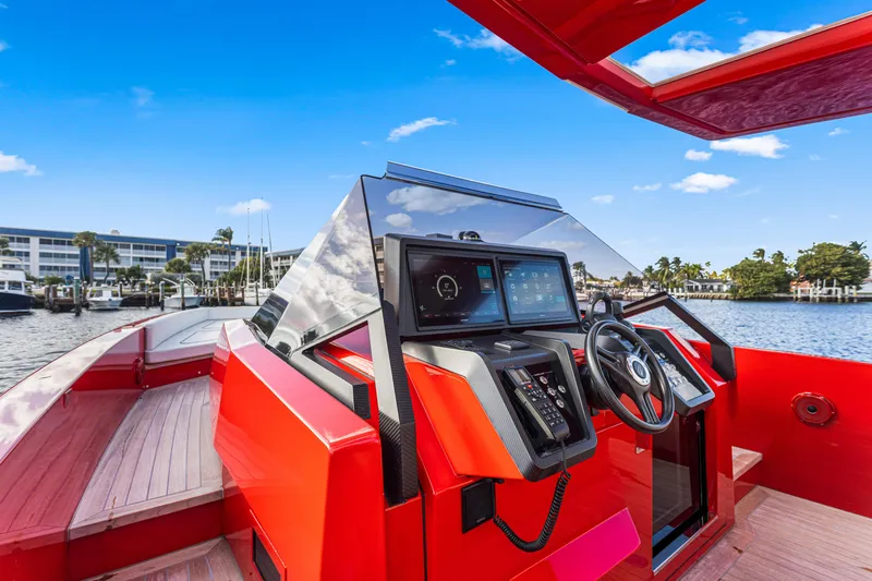 Slide: The Image of Red 2021 Wally 48 yacht cockpit with modern controls, docked by waterfront buildings. - 12