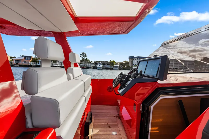 Slide: The Image of Red 2021 Wally 48 yacht interior with modern helm and seating, docked by waterfront homes. - 18