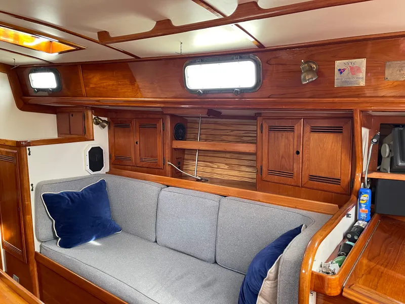 Slide: The Image of Cozy interior of 1985 Chuck Paine Intrepid 40 sailboat with wooden cabinetry and gray seating. - 2