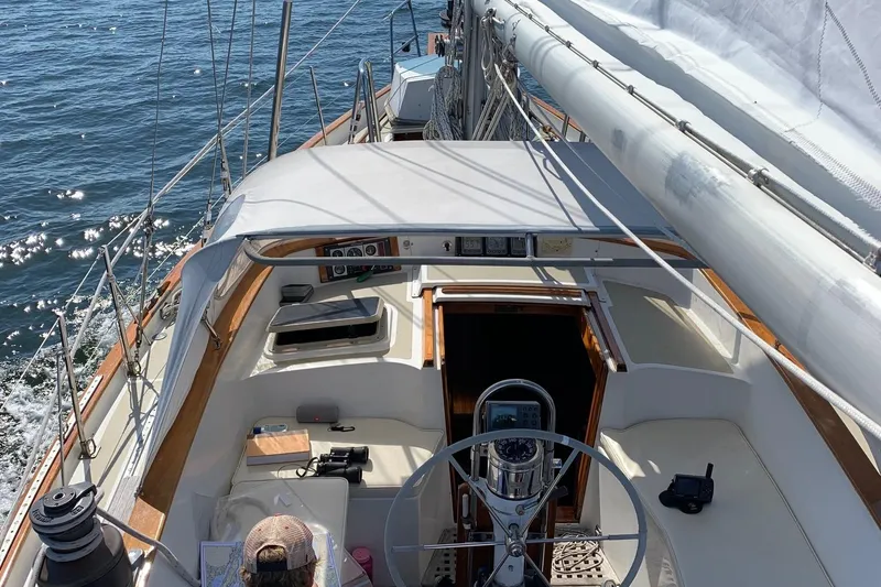 Slide: The Image of 1985 Chuck Paine Intrepid 40 Center Cockpit sailboat on open water, featuring helm and seating area. - 32