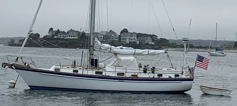 Slide: The Image of 1985 Chuck Paine Intrepid 40 Center Cockpit sailboat anchored near coastal homes. - 39