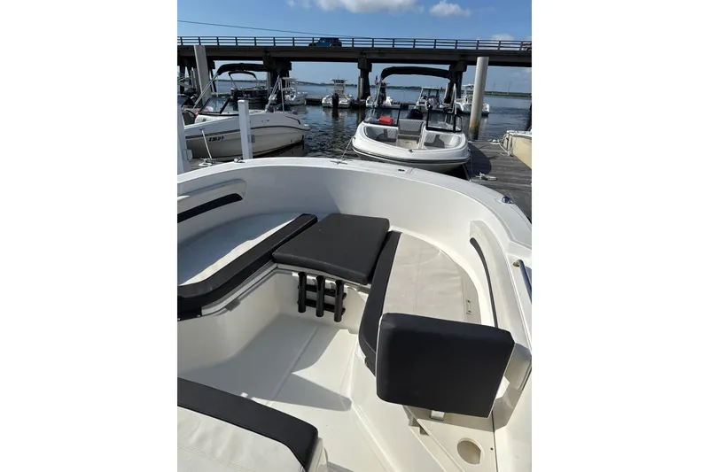 Slide: The Image of 2023 Trophy CC24 boat interior with seating, docked near other boats under a bridge. - 6