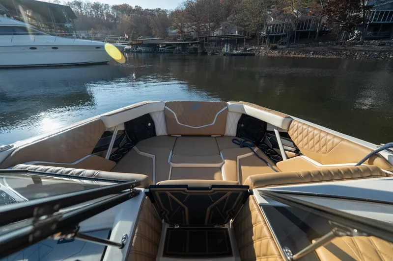 Slide: The Image of 2026 Tigé 24RZX boat interior with tan seating, docked on a calm lake. - 13