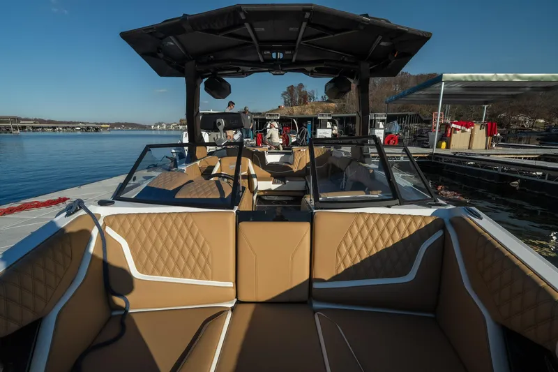Slide: The Image of 2026 Tigé 24RZX boat interior with tan seating, docked by a serene lake. - 14