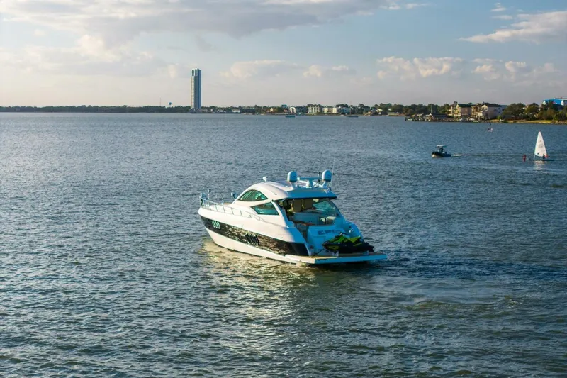 Slide: The Image of 2013 Cruisers Yachts 540 Sports Coupe on a serene lake with distant cityscape. - 46