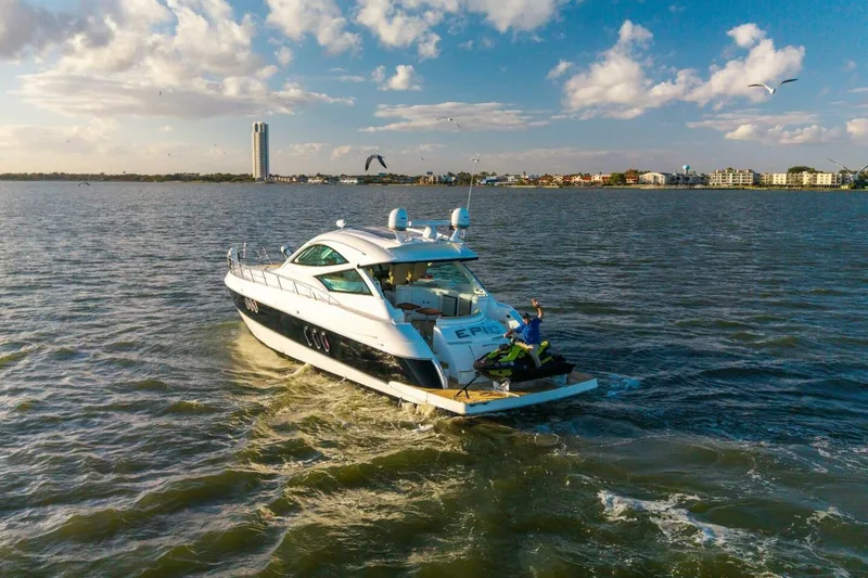 Slide: The Image of 2013 Cruisers Yachts 540 Sports Coupe on open water, clear sky, and distant cityscape. - 50