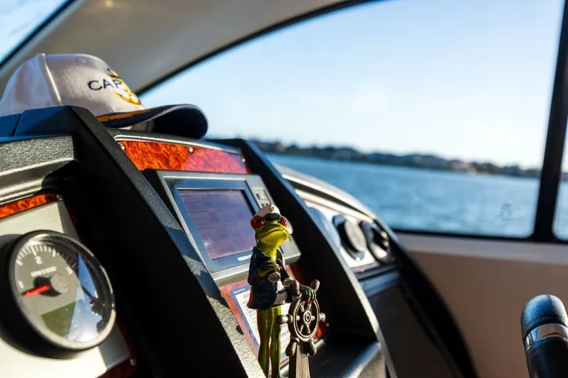 Slide: The Image of 2013 Cruisers Yachts 540 Sports Coupe dashboard with captain's hat and frog figurine. - 23
