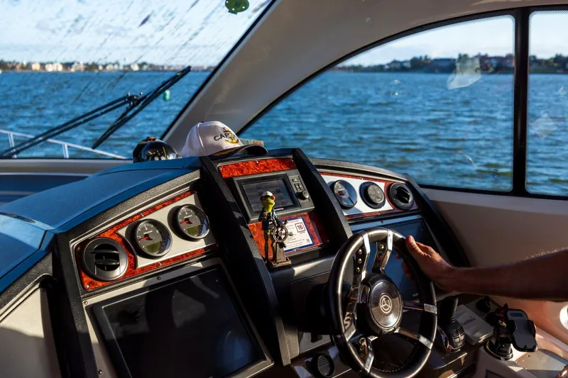Slide: The Image of 2013 Cruisers Yachts 540 Sports Coupe helm with gauges, steering wheel, and water view. - 5