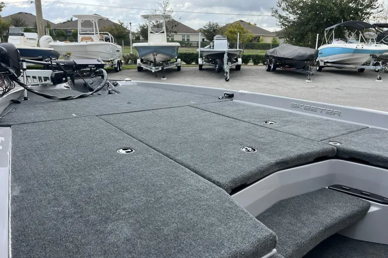 Slide: The Image of 2026 Skeeter ZXR21 SE boat with carpeted deck, parked among other boats. - 3