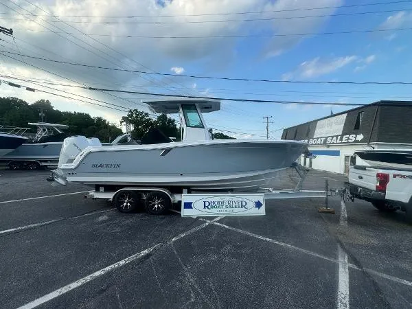 Slide: The Image of 2026 Blackfin 252 CC boat on trailer at dealership, clear sky background. - 9