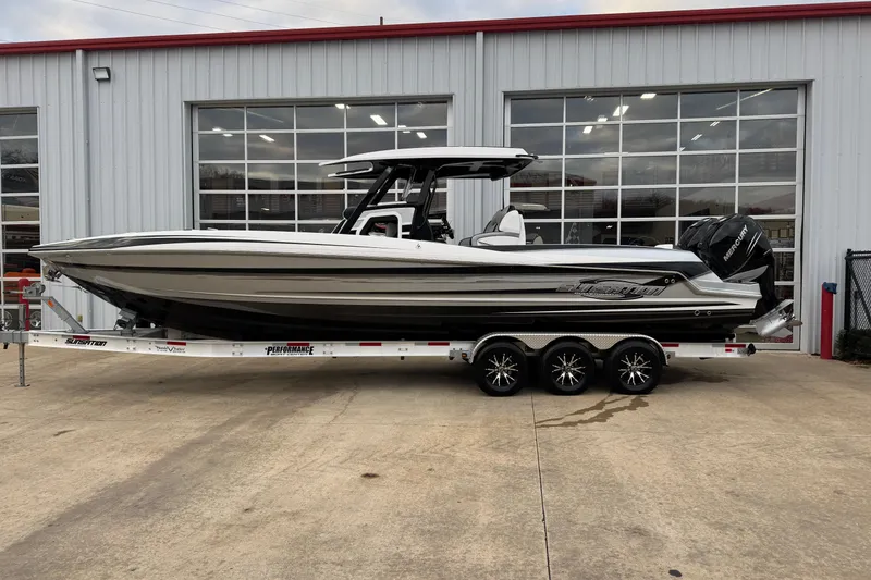 The Image of 2023 Sunsation 32CCX boat on trailer outside a garage, showcasing sleek design and powerful engines. - 0