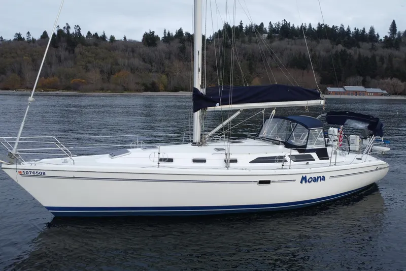 Slide: The Image of 1998 Catalina 42 MkII sailboat named "Moana" on calm water, forested shoreline in background. - 2