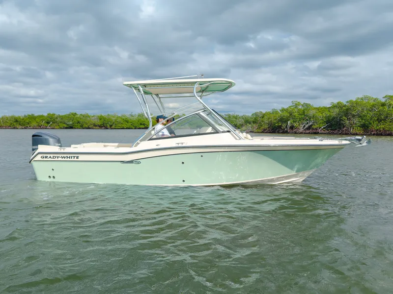 Slide: The Image of 2018 Grady-White Freedom 255 boat on calm water with lush green shoreline. - 12