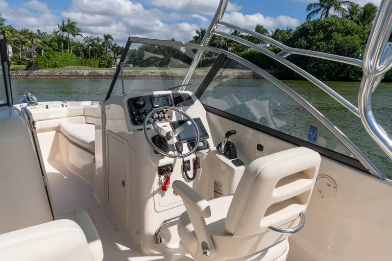 Slide: The Image of 2018 Grady-White Freedom 255 boat interior with steering wheel and seating, on a sunny day. - 18