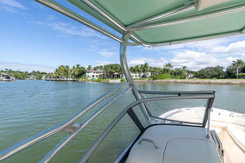 Slide: The Image of 2018 Grady-White Freedom 255 boat cruising near waterfront homes under clear blue skies. - 19