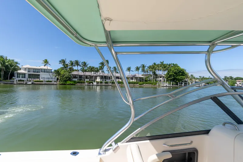 Slide: The Image of 2018 Grady-White Freedom 255 boat on calm water, luxury waterfront homes in background. - 20