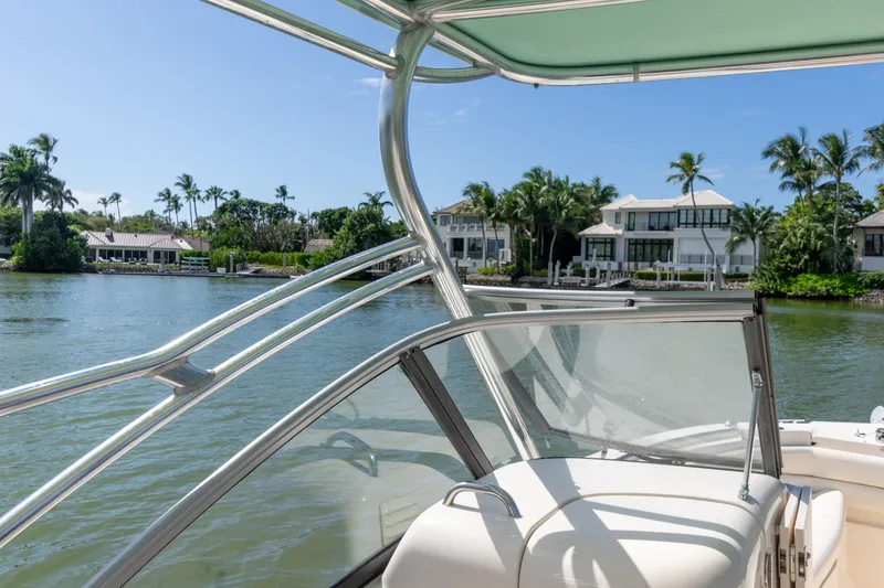Slide: The Image of 2018 Grady-White Freedom 255 boat on a scenic waterfront with palm trees and houses. - 22