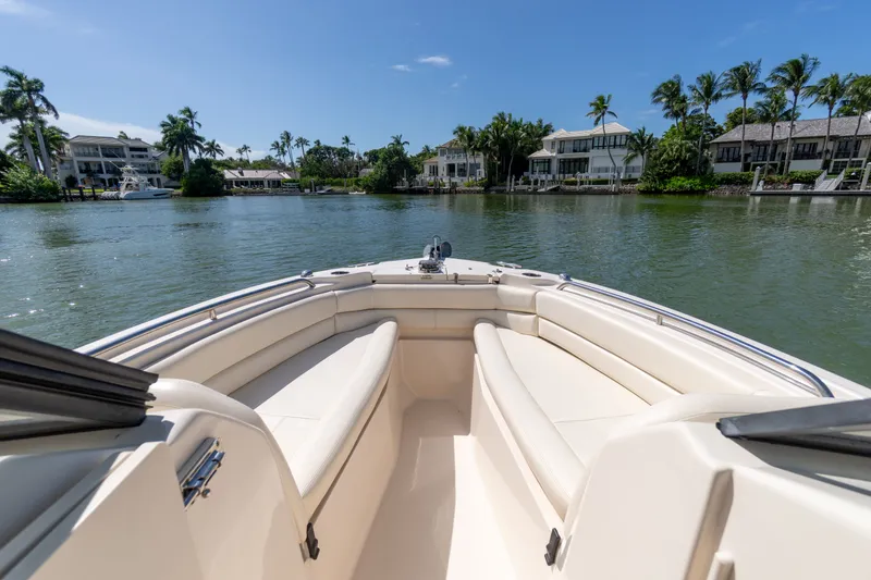 Slide: The Image of 2018 Grady-White Freedom 255 boat on a scenic waterway with palm trees and houses. - 23