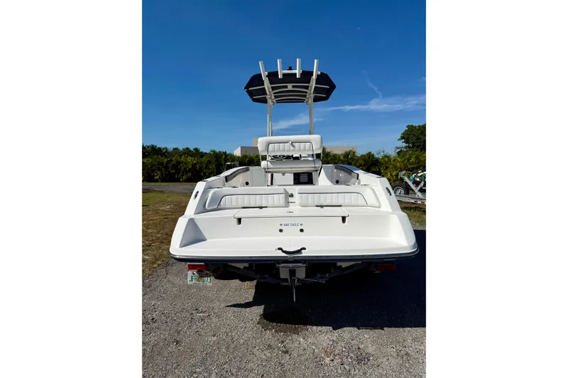 Slide: The Image of 2018 Yamaha Boats 210 FSH Sport, rear view, parked on gravel under clear blue sky. - 18
