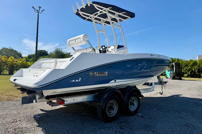 Slide: The Image of 2018 Yamaha Boats 210 FSH Sport on trailer, parked outdoors under clear blue sky. - 19