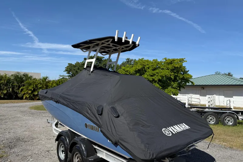 Slide: The Image of 2018 Yamaha Boats 210 FSH Sport covered on trailer, outdoors under clear sky. - 25