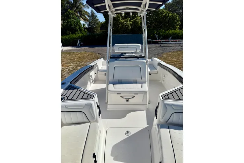 Slide: The Image of 2018 Yamaha Boats 210 FSH Sport interior with seating and console, surrounded by greenery. - 7