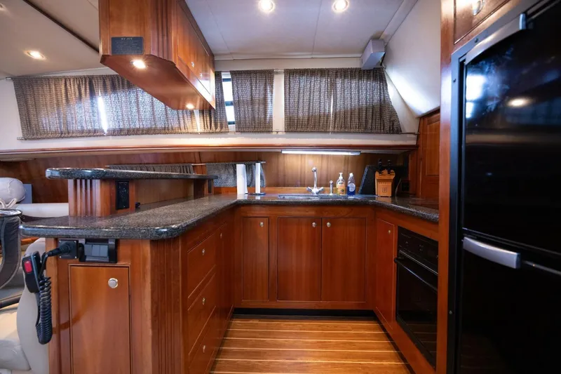 Slide: The Image of Luxurious 2005 Cruisers Yachts 455 Express Motoryacht kitchen with wood cabinetry and modern appliances. - 3