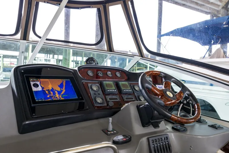 Slide: The Image of 2005 Cruisers Yachts 455 Express Motoryacht helm with navigation display and wooden steering wheel. - 6