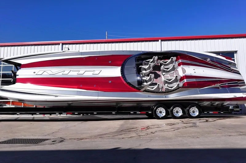 Slide: The Image of 2016 MTI 48 powerboat with sleek red and white design, parked on a trailer. - 12