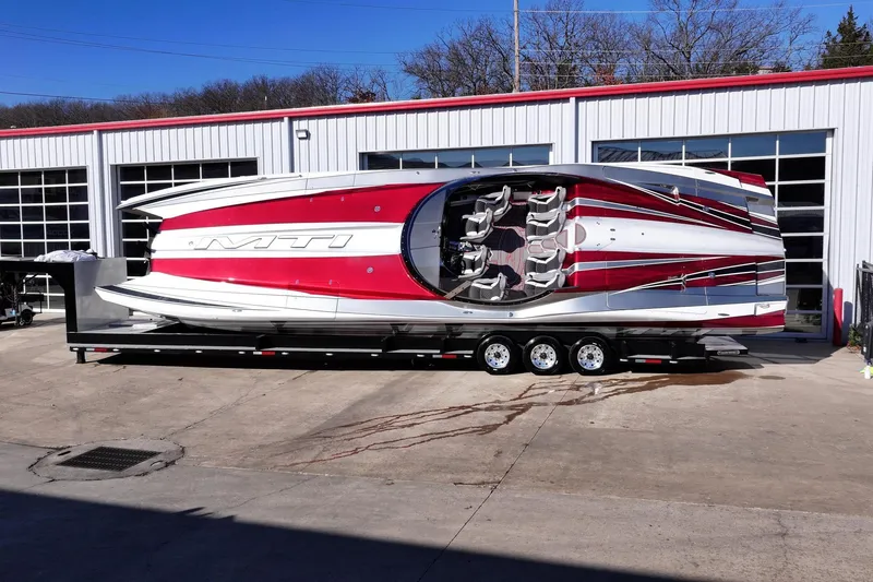 Slide: The Image of 2016 MTI 48 powerboat on trailer, red and white design, parked outside garage. - 13