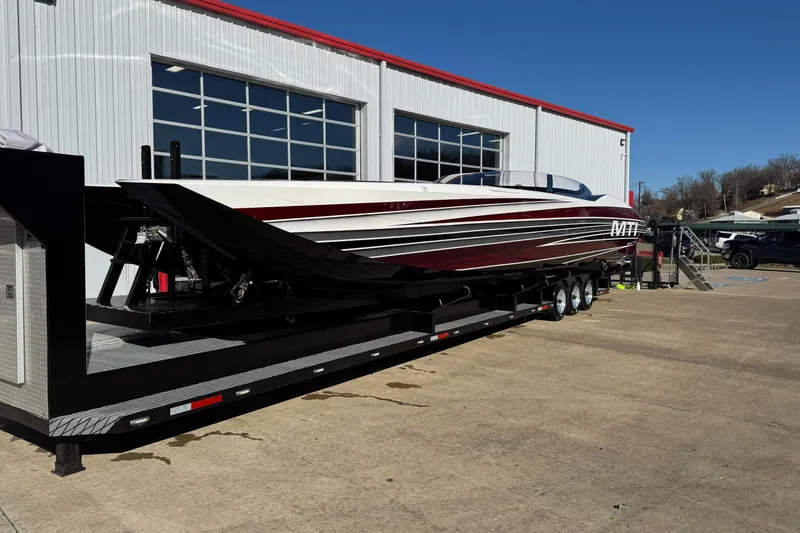 Slide: The Image of 2016 MTI 48 speedboat on trailer outside a garage, under clear blue sky. - 15