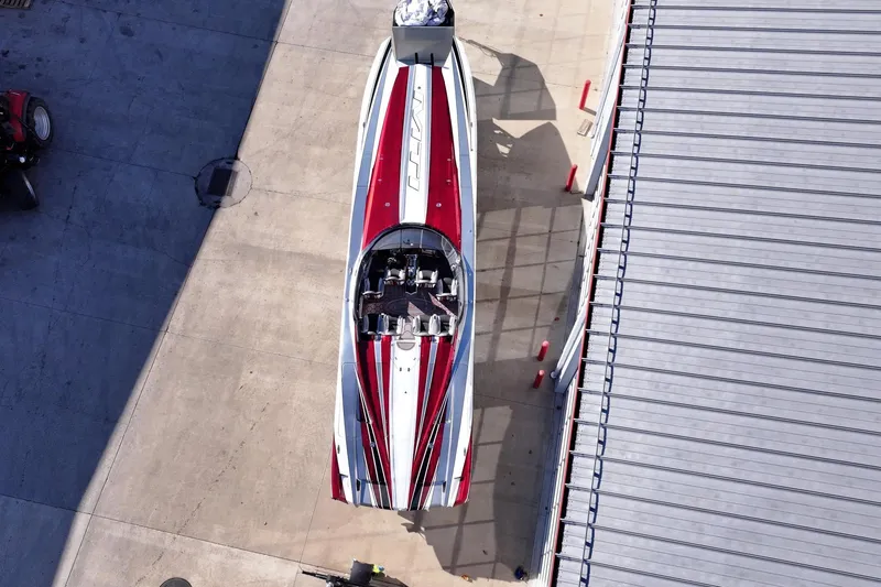 Slide: The Image of Aerial view of a 2016 MTI 48 speedboat with red and white design on concrete. - 2