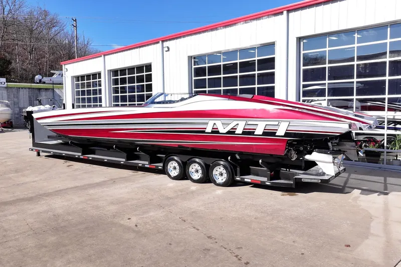 Slide: The Image of 2016 MTI 48 powerboat with red and white design on a trailer outside a garage. - 30