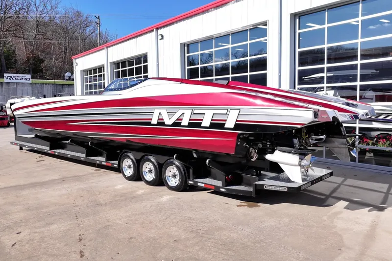 Slide: The Image of Red and white 2016 MTI 48 speedboat on trailer outside a garage. - 31