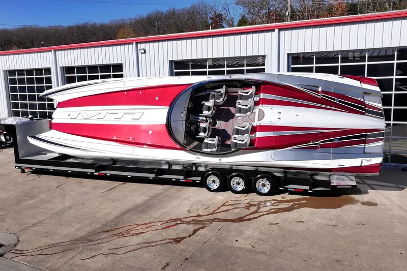 Slide: The Image of 2016 MTI 48 powerboat with red and white design on a trailer outside a garage. - 4